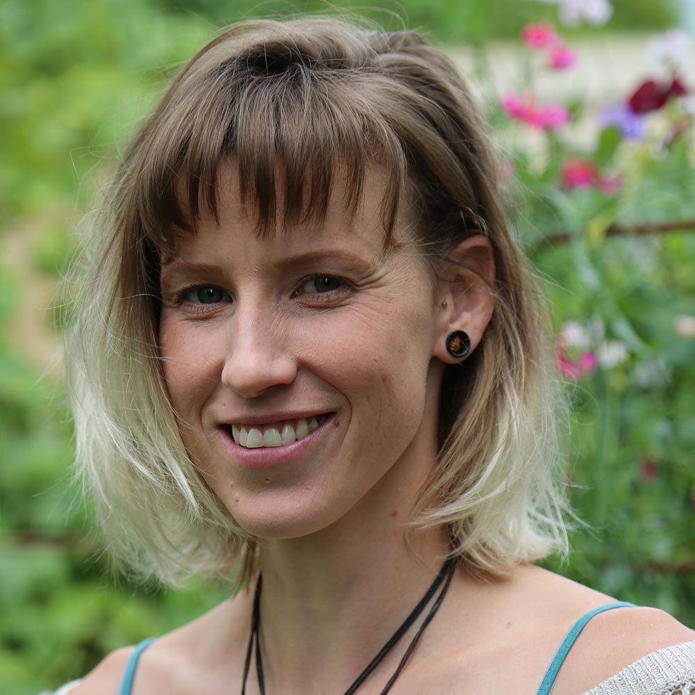 Portrait photo of Lilly Van Epen smiling at camera in a sunny garden