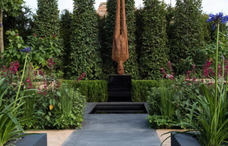 A large metal sculpture of an upside down person in a modern stylish garden