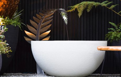 A stylish water feature with a large white bowl and curved metal leaf