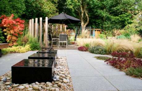 Three black cuboid water features in a modern garden