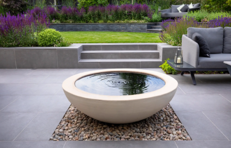 A larger white bowl water feature in a modern garden