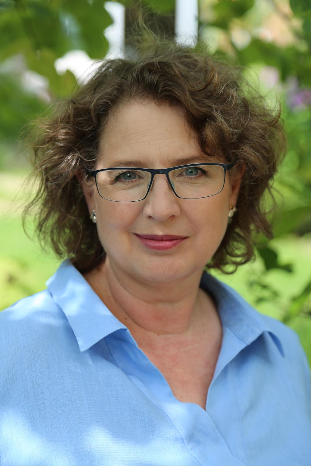 Portrait photo of Rosemary Coldstream smiling at camera in a sunny garden